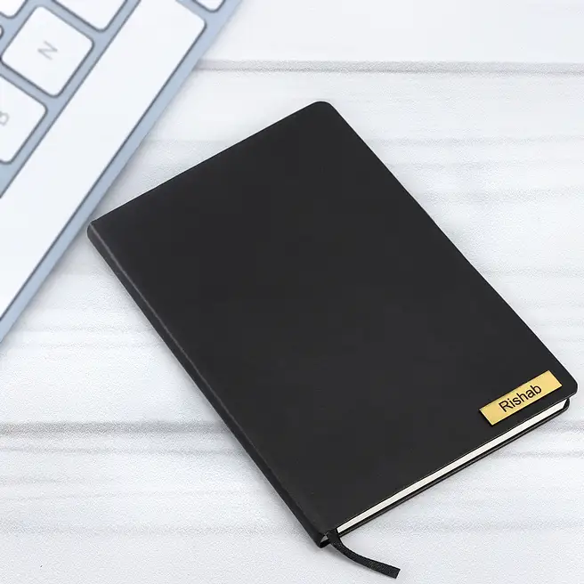Angled view of personalized black hard cover notebook with durable binding and custom name plate.